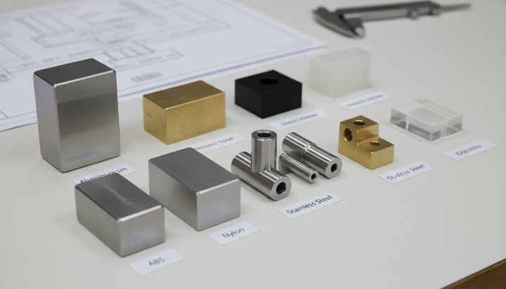 Material samples used in CNC machining including aluminum 6061, stainless steel 304, brass, and engineering plastics.